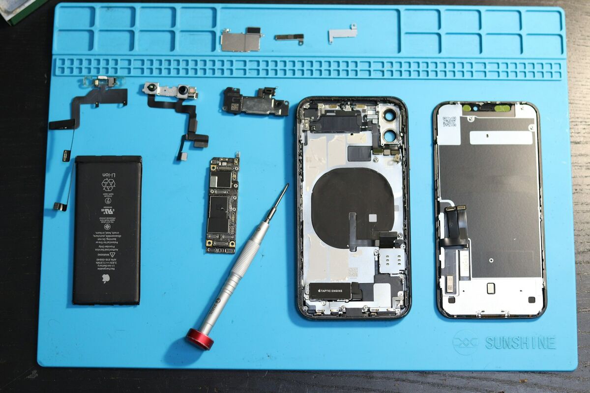 Componentes desarmados de un teléfono sobre base azul para reparación